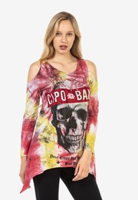 Bunt gemusterte Cold-Shoulder-Bluse mit einem Totenkopf-Graphic und Strasssteinen, Batikmuster in Rot, Gelb und Schwarz sowie asymmetrischem Saum.