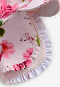 Bloemige zwemshorts met een roze en witte kleurenschema, gemaakt van gladde stof met rimpelaccenten langs de zoom en een bloemenpatroon.