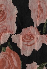 Tessuto floreale con rose rosa su uno sfondo nero; texture morbida e trasparente con dettagli arricciati in vita; accenti di foglie verdi.