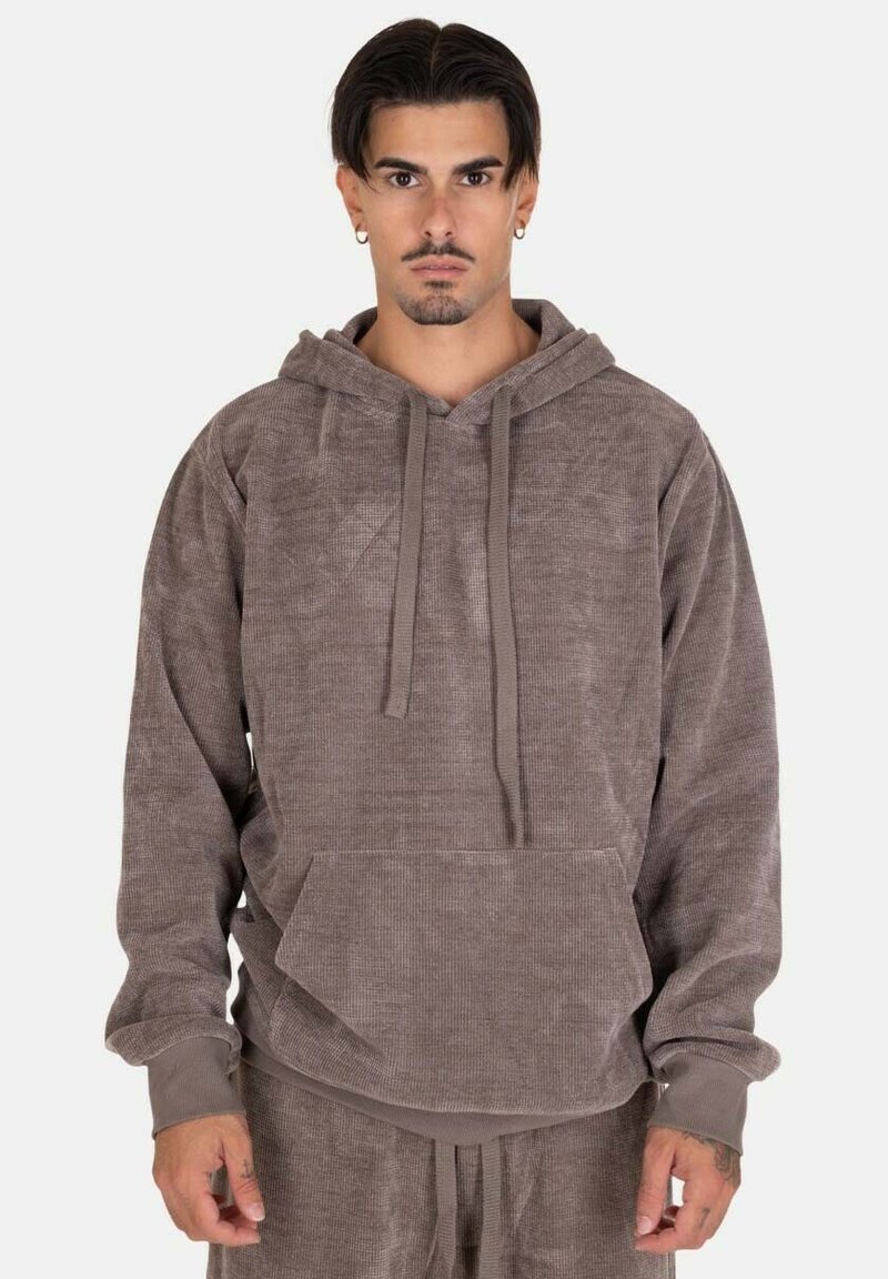 Hoodie in velluto a coste marrone con tasca a marsupio, cappuccio regolabile con coulisse e polsini a coste. Tessuto morbido, vestibilità rilassata e colore tenue.