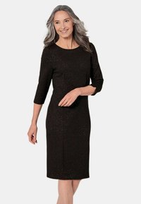 Robe noire jusqu'aux genoux avec des manches trois-quarts, tissu texturé présentant de subtils éclats métalliques, encolure ronde et silhouette ajustée.