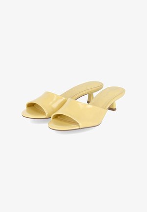 Mules jaunes à bout ouvert avec petit talon, finition brillante et style slip-on, présentées côte à côte sur fond blanc.