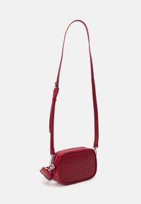 Červená kabelka přes rameno z umělé kůže s obdélníkovým tvarem, s embosovaným krokodýlím vzorem a nastavitelným popruhem. Viditelné stříbrné detaily.