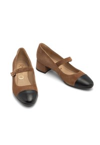 Brown suede mary janes with a black leather cap toe, block heel, and adjustable strap. Interior features a light tan lining.