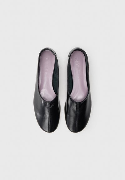 Scarpe slip-on in pelle nera con una texture liscia, dotate di punta arrotondata e un sottopiede viola a contrasto. Nessun accessorio o hardware visibile.