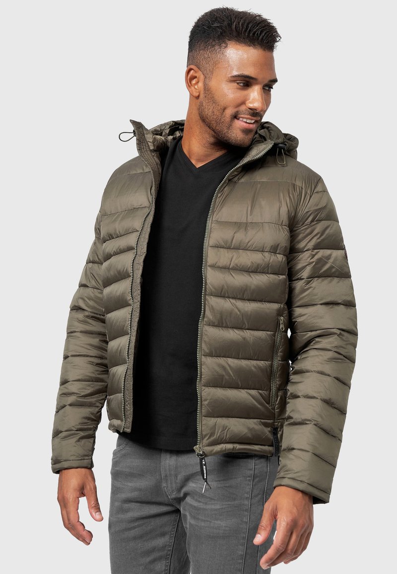 Chaqueta tipo puff verde oliva con cierre frontal, capucha y diseño de paneles horizontales. Cuenta con puños elásticos y dos bolsillos laterales. Tela texturada.