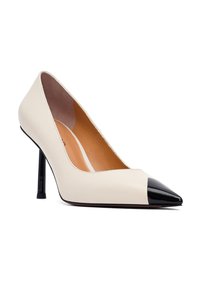 Beżowe skórzane szpilki z wąskim noskiem i błyszczącym czarnym czubkiem, z eleganckim obcasem typu stiletto i gładką podszewką wewnętrzną.