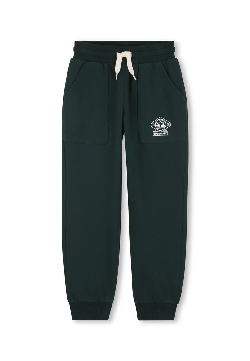 Groene trainingsbroek van zacht materiaal, met twee zijzakken, een elastische tailleband met een koord en een wit logo op de linkerdij.
