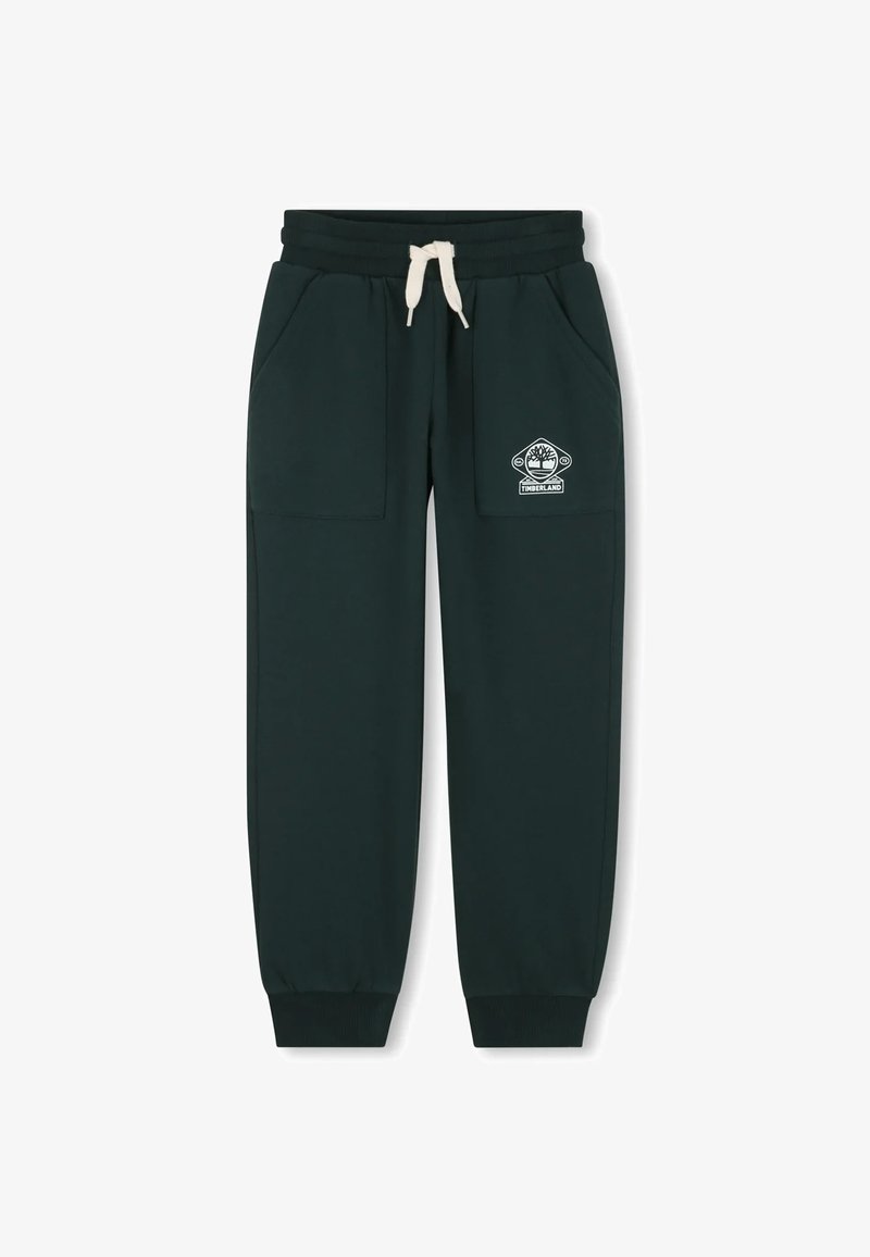 Groene trainingsbroek van zacht materiaal, met twee zijzakken, een elastische tailleband met een koord en een wit logo op de linkerdij.