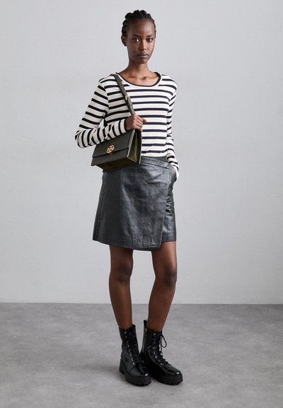 Black leather mini skirt, striped long-sleeve shirt, green handbag with gold hardware, and black lace-up ankle boots. Smooth texture.