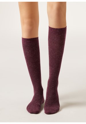Kniestrümpfe in Burgunderrot mit einer gesprenkelten Textur. Weiches Material, figurbetonte Form und ein gerippter Bund am oberen Ende. Geeignet für den Freizeitgebrauch.
