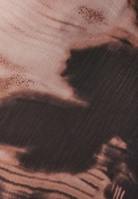 Gelaagd textiel met een verloop van beige en donkerbruin tinten, met subtiele lijnen en abstracte patronen, wat een gelaagde uitstraling geeft.