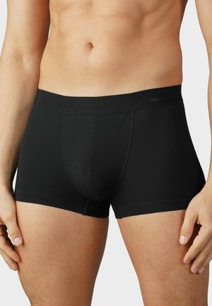 Tronc en coton noir avec une taille lisse et une coupe ajustée. Présente une couture à l'avant pour la forme et le soutien.