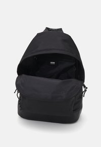 Zaino nero realizzato in tessuto resistente, dotato di chiusura con zip, ampia apertura e tasca interna. Texture liscia con design minimal.