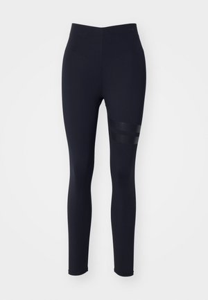Leotard negro hecho de tela elástica, con una cintura alta y acentos de panel de malla en el muslo con rayas horizontales.