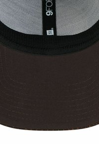 Schwarze und graue Mesh-Baseballmütze mit sichtbaren Nähten und einem "9FORTY New Era"-Etikett im Inneren der Mütze.