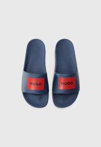 Marineblå slippersandaler med teksturert fotseng og bred rem med en rød rektangulær logo. Laget av syntetisk materiale, uformelt design.