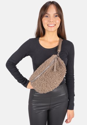 Braune, strukturierte, flauschige Umhängetasche mit Reißverschluss aus Silber und Lederriemen, die über einem schwarzen Oberteil getragen wird und ein lässiges Design zeigt.