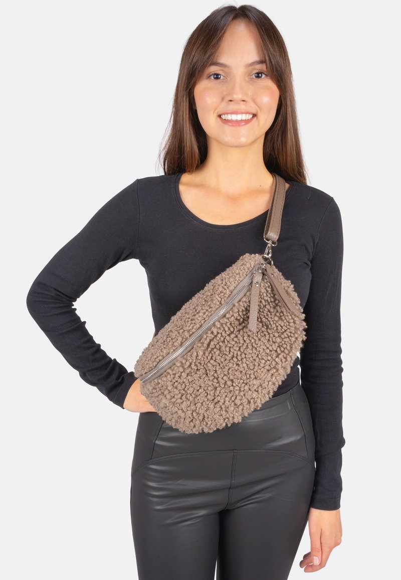 Braune, strukturierte, flauschige Umhängetasche mit Reißverschluss aus Silber und Lederriemen, die über einem schwarzen Oberteil getragen wird und ein lässiges Design zeigt.