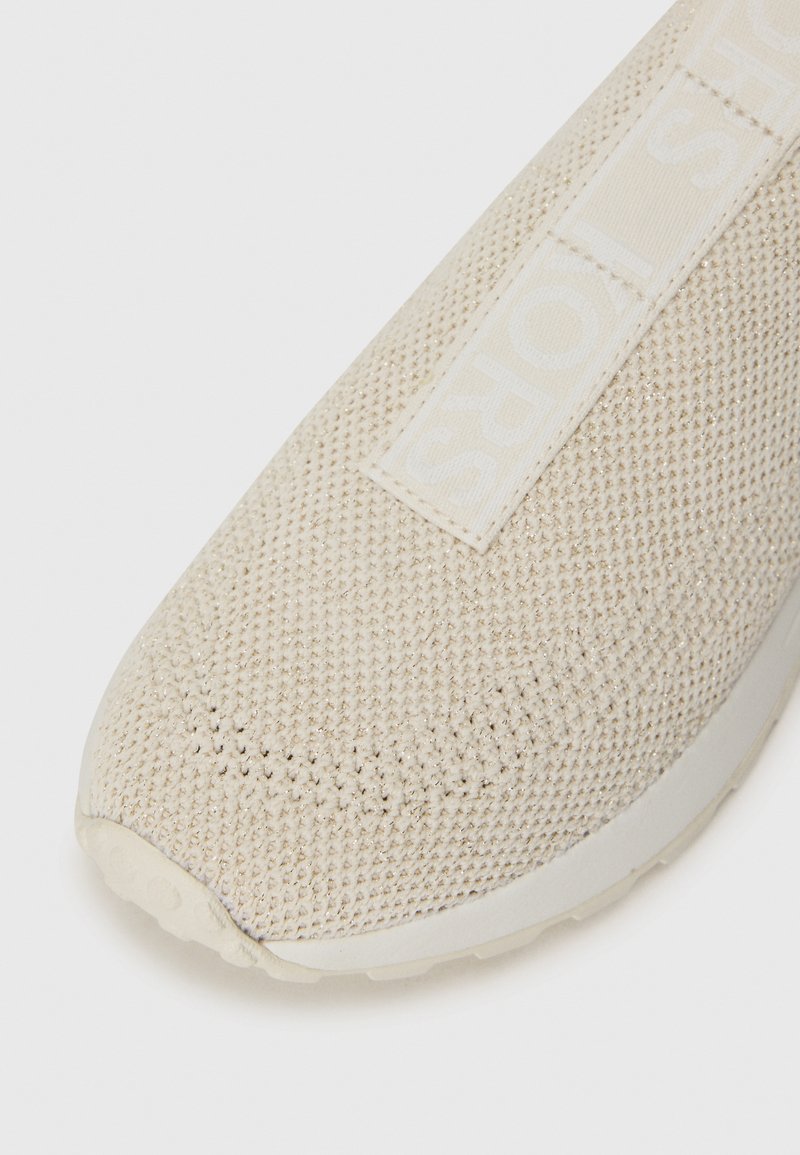 Beige sneaker met een bovenwerk van mesh breisel, versterkte neus en platte zool. Heeft een gestructureerd oppervlak en een contrasterende logo-band over de bovenkant.