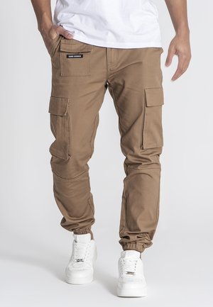 Khaki cargobroek gemaakt van duurzaam materiaal, met zijzakken, elastische manchetten en een merkembleem boven de linkerzak.