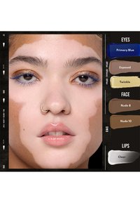 Primo piano di una persona con vitiligine che indossa ombretto dorato, mascara blu, lucidalabbra nude e un anello al naso, insieme a campioni di colori per il trucco.