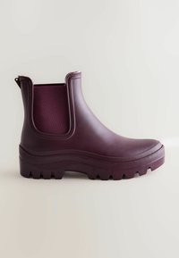 Bottine en caoutchouc bourgogne avec un panneau latéral en élastique texturé, semelle à crampons épaisse et design sans couture pour durabilité et résistance à l'eau.