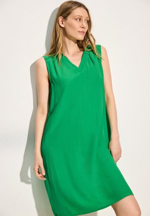 Robe verte sans manches avec un décolleté en V, fabriquée en tissu léger, dotée d'une coupe ample et d'une texture douce, arrivant au-dessus du genou.