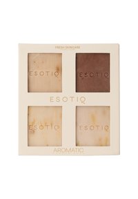 Zestaw czterech kwadratowych mydeł prysznicowych w różnych odcieniach kremu i brązu, opatrzonych napisem "ESOTIQ", mieszczący się w kremowym opakowaniu z złotym tekstem.