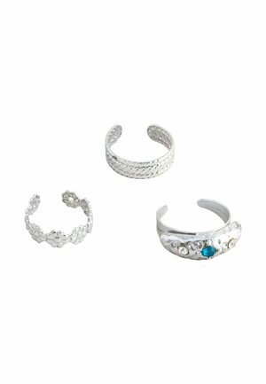Drei verstellbare silberne Zehenringe: einer mit geflochtenem Muster, einer mit floralem Design und einer mit eingebetteten blauen und klaren Steinen.