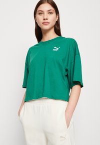 T-shirt in cotone verde con vestibilità morbida, maniche corte e scollatura rotonda. Presenta un logo Puma bianco sul petto.