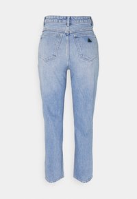 Jean en denim bleu clair taille haute avec deux poches arrière, coutures visibles et un petit logo triangulaire noir sur la poche droite.