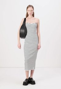 Vestido bodycon riscado em preto e branco, mala de ombro em couro preto, sapatos de salto grosso pretos, textura suave, design ajustado.