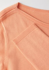 Sweter w kolorze brzoskwiniowym, wykonany na drutach, z okrągłym dekoltem, prążkowanymi brzegami i gładką fakturą. Materiał dobrze się układa i posiada detale w samych szwach.