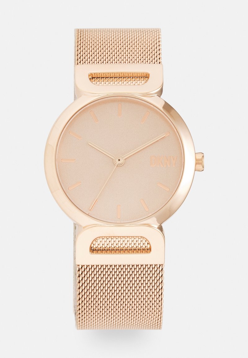 Montre bracelet DKNY en or rose avec bracelet en maille, cadran minimaliste avec index horaires et aiguilles fines, sans chiffres sur le cadran.