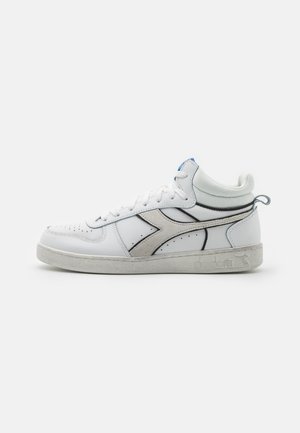 Hvid midt-top sneaker med grå accenter, snøredesign, polstret krave og struktureret sål mod en ensfarvet lys baggrund.