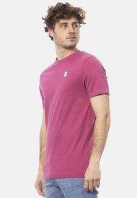 T-shirt aderente a maniche corte in cotone fucsia vivace, con un piccolo logo bianco sul petto e scollatura rotonda.