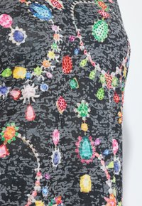 Černá tkanina s texturovaným vzorem, zdobená barevnými tvaru drahokamů v různých velikostech, včetně modré, červené, růžové a zelené.