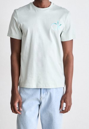 Světle zelené bavlněné tričko s krátkými rukávy a kulatým výstřihem. Na levé straně hrudi se nachází jemné modré logo "ck".