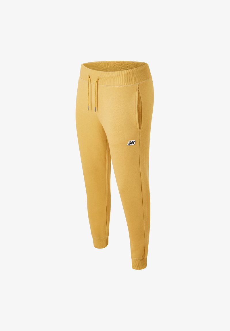 Yellow sweatpants made of soft fabric with a tapered design, elastic waistband, drawstring, and side pockets. Features a logo on the thigh.