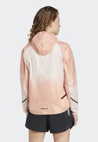 Veste à capuche légère dégradée de pêche à blanc. Dispose d'inserts en maille respirante, de poches zippées et d'accents réfléchissants.