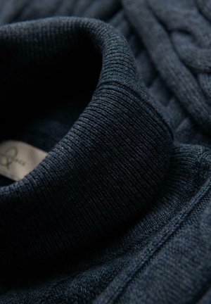 Mörkblå stickad tröja med hög, ribbad krage. Tyget har ett strukturerat mönster med en slät yta. Etiketten är synlig inuti kragen.