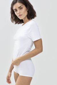 T-shirt blanc à manches courtes en tissu doux, avec un design légèrement ajusté, porté avec un bas taille haute blanc. Apparence minimaliste et sans couture.