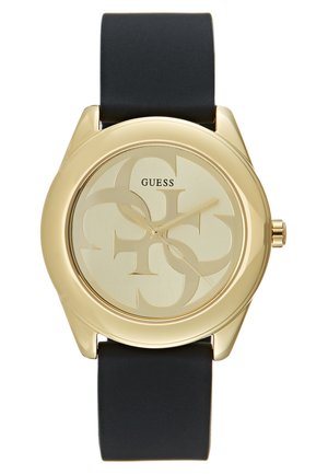 Gold-tone watch with a round case, black silicone strap, and a light gold dial featuring a logo pattern and simple hour markers.