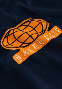Tumesinine t-särk, millel on suur oranž maakera graafika ja valge tekst "BAKER by TED BAKER." Sile kangas, erk värvitoon ja selge disain.