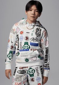 Felpa con cappuccio e pantaloni jogger, bianchi con loghi e motivi colorati. Presenta polsini e orlo a costine, con una vestibilità comoda e una texture morbida.