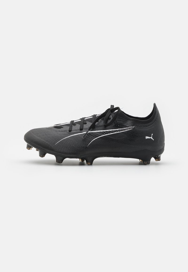Crampon de soccer noir avec un revêtement texturé, un système de laçage et un design élégant avec des accents blancs. Écrous dorés sur la semelle.