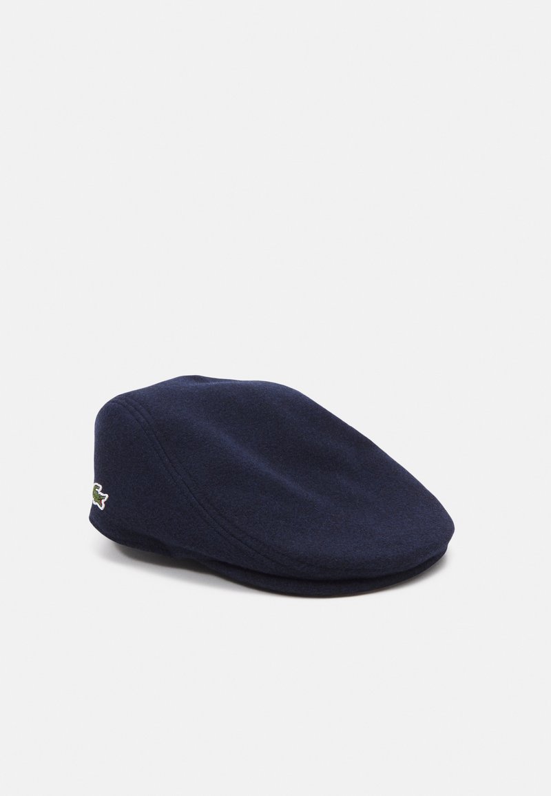 Navy wool cap with a rounded crown and short brim, featuring a small embroidered logo on the side. Soft texture and sleek design.