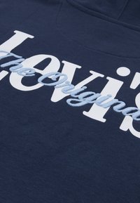 Μπλε σκούρο φούτερ με κουκούλα, διακοσμημένο με λευκή και ανοιχτό μπλε κεντητική, με το κείμενο "Levi's The Original" να ξεχωρίζει στο στήθος.