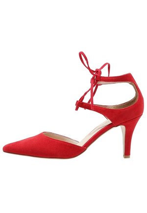 Scarpa rossa in camoscio con punta appuntita, tacco alto, cinturino alla caviglia con chiusura a fiocco, tacco sottile di altezza media e lati aperti.